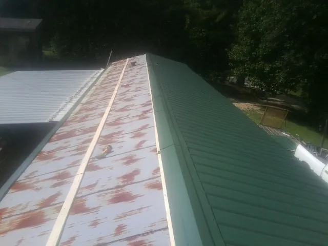 Old rusted panels beside newly installed green metal roofing — Wind Damage Roof Repair by Roofing Brothers in Dumont